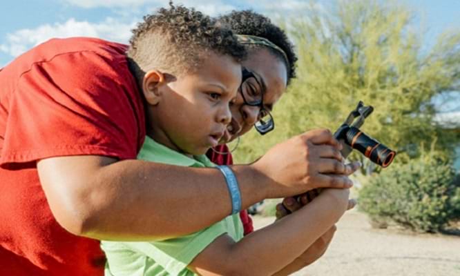 a child in a green shirt looking at the biodiversity photos with an adult